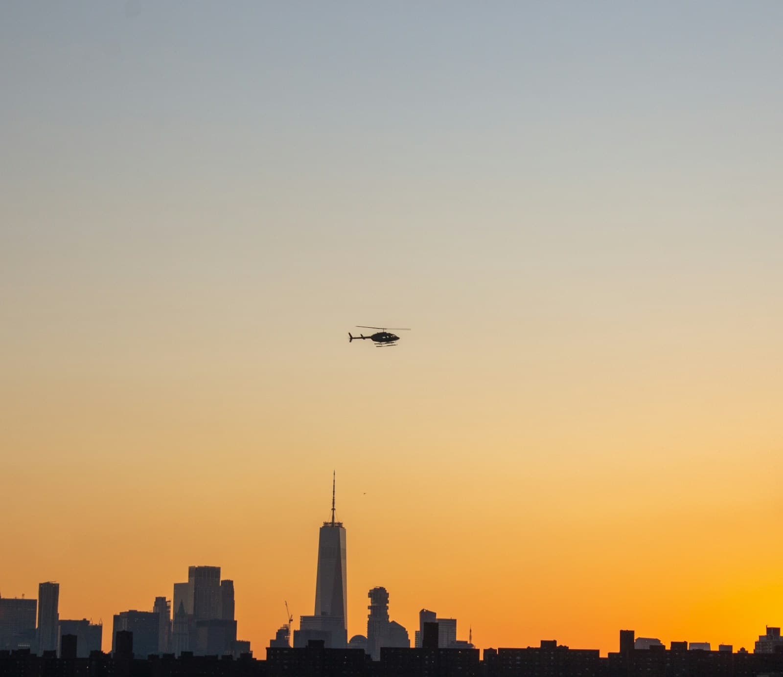 Helicóptero sobrevolando una ciudad al atardecer